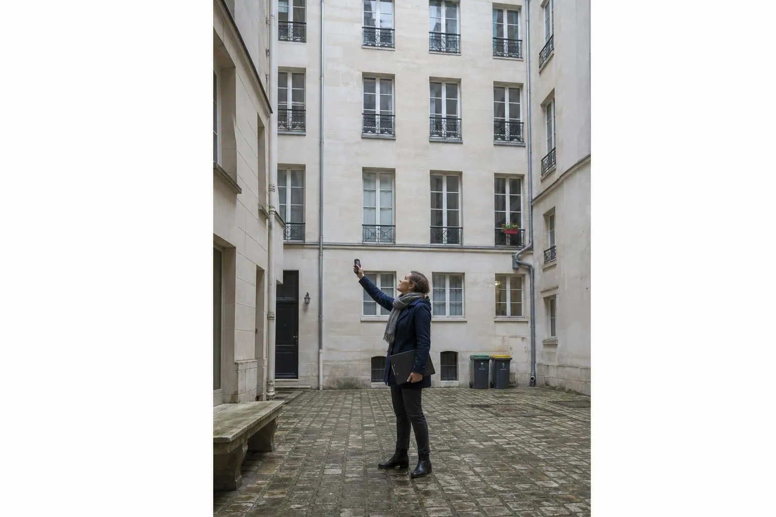 Diagnostiqueuse relevant les menuiseries d un immeuble ancien depuis la cour interieure